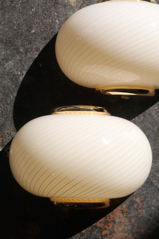 Sæt á 2 stk. vintage Murano creme væglamper med hvid swirl mønster og beslag i messing. Perfekt størrelse til din entré, i køkkenet, på badeværelset eller som læselamper i soveværelset. Super nemme at montere. Mundblæst i Italien, 1960/70erne og varierer i udtrykket. Størrelse 22x15 cm. 