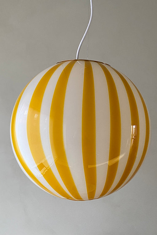 Ny Murano candy pendel loftlampe i en bolsje kombination af gul og hvid. Mundblæst glas i rund form med vertikale striber. E27 fatning. Kommer med justerbart messingbelagt ophæng samt transparent ledning.   Håndlavet i Italien.   D:40 cm  
