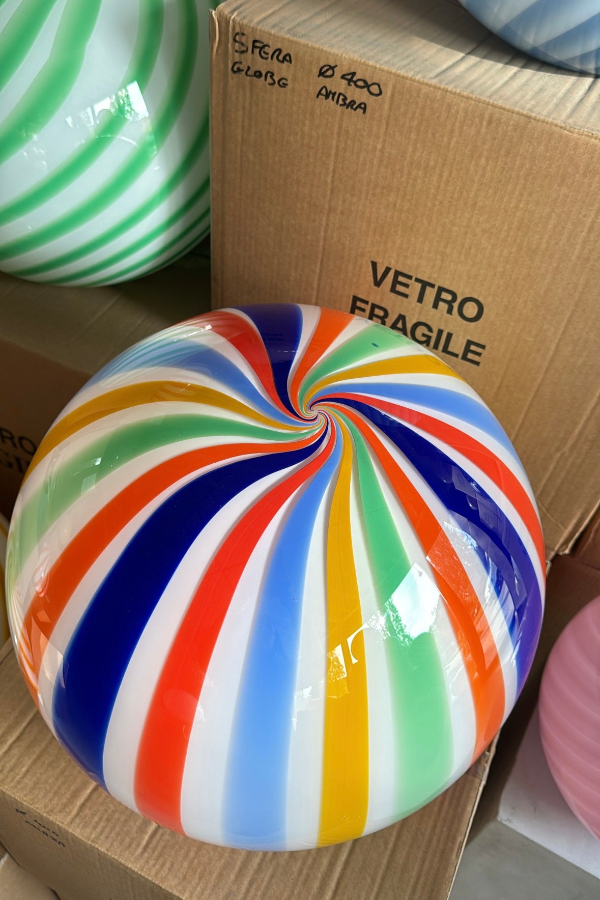 Ny stor Murano Candy tivoli pendel loftlampe med striber i rød, blå, gul, lyseblå, orange og mørkeblå. Mundblæst glas i rund form med vertikale striber. E27 fatning. Kommer med justerbart ophæng. Håndlavet i Italien