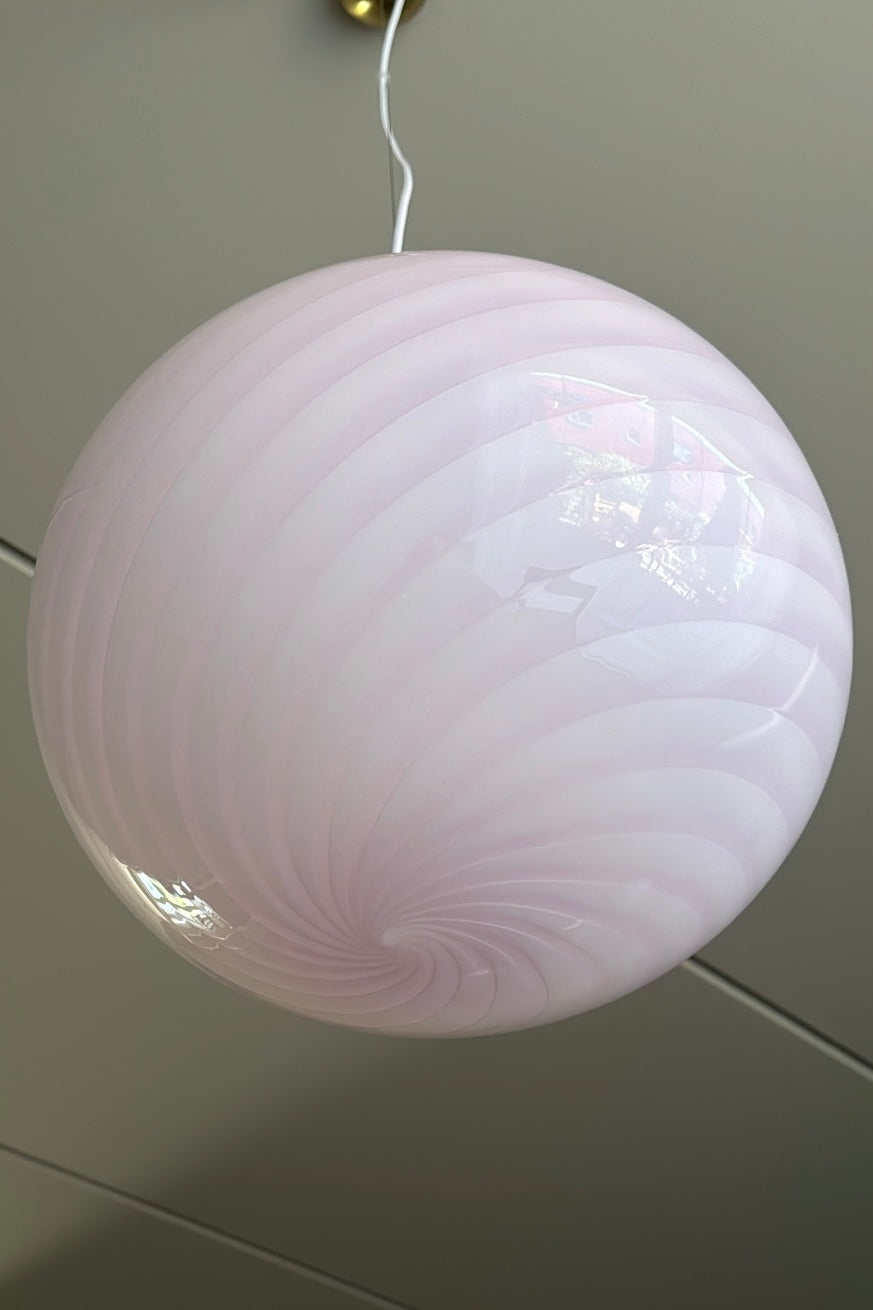 Ny Murano candy pendel loftlampe i en fin blød lyserød nuance. Mundblæst glas i oval form med swirl mønster. E27 fatning. Kommer med justerbart messingbelagt ophæng samt transparent ledning.  Håndlavet i Italien.  D:40 cm  