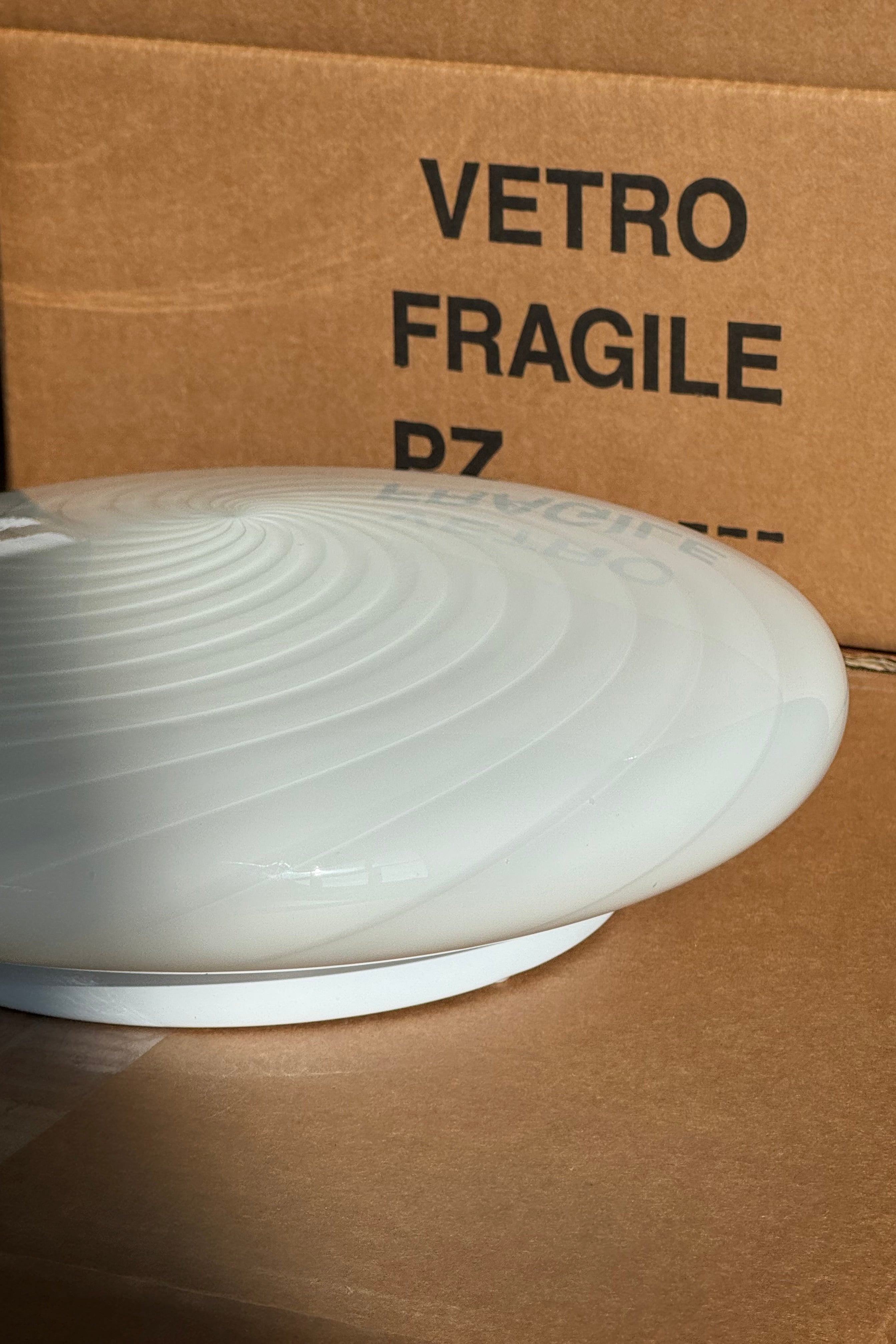 Ny Murano Candy plafond loftlampe / væglampe med swirl. Mundblæst i hvid opal glas i cirkulær, flad form. E27 fatning. Kommer med hvid bagplade. Håndlavet i Italien.
D:30 cm H: 11 cm