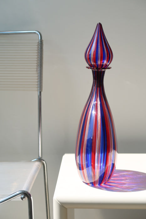 Særlig stor vintage Murano vase med låg i dybe nuancer af rød, blå og kobber. Mundblæst i glas i en teknik som primært er kendt fra glashusene Venini, Gio Ponti og Fratelli Toso. Håndlavet i Italien, 1970erne. 