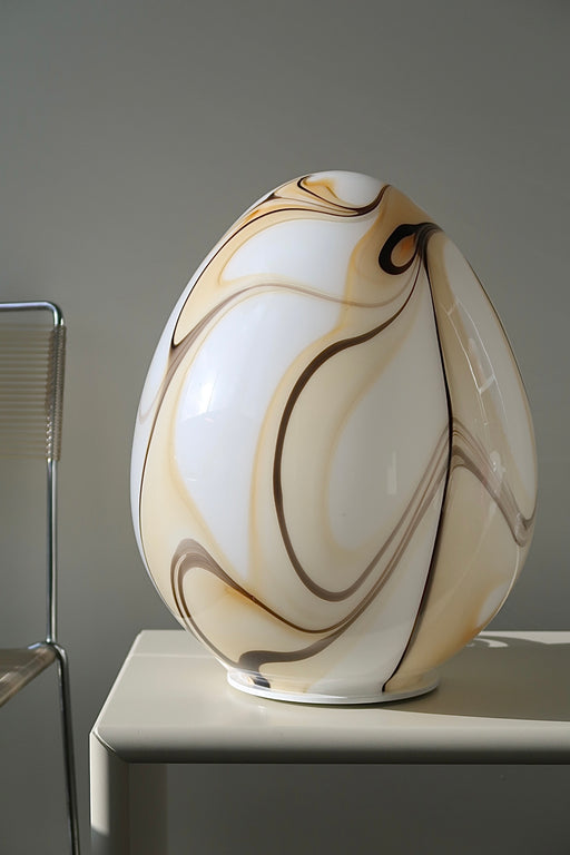 Vintage stor Murano egg lampe i hvid glas med mønster i nuancer af gul, karamel og mokka. Mundblæst i en smuk oval form som et æg og er derfor kendt som ''egg lamp''. Helt fantastisk, skulpturel lampe. Håndlavet i Italien, 1960/70erne. ⁠H: 45 cm D: 32 cm⁠