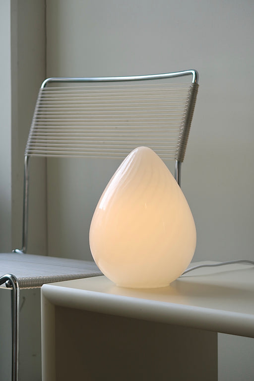 Vintage Murano egg lampe i hvid glas med swirl. Mundblæst i en smuk oval form som et æg og er derfor kendt som ''egg lamp''. Helt fantastisk, skulpturel lampe. Håndlavet i Italien, 1960/70erne. Kommer med ny hvid ledning. ⁠H: 21 cm D: 14 cm