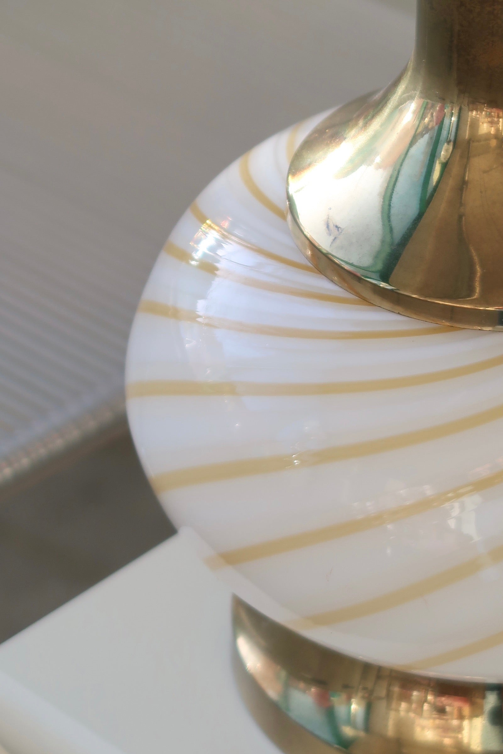 Vintage Murano lampefod i glas med hvid og gul swirl og messing detaljer. Mundblæst i rund form og har dobbelt fatning - dvs. den lyser både i glasbunden og i toppen. Lampen afgiver et meget hyggeligt lys og har en fantastisk swirl. Håndlavet i Italien, 1970erne. H:28 cm D:20 cm 