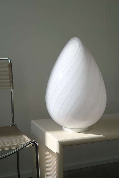 Vintage stor Murano egg lampe i hvid glas med swirl. Mundblæst i en smuk oval form som et æg og er derfor kendt som ''egg lamp''. Helt fantastisk, skulpturel lampe. Håndlavet i Italien, 1960/70erne. Kommer med ny hvid ledning. ⁠H: 42 cm D: 27 cm⁠