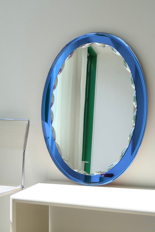 Stort vintage italiensk spejl i ovalt facetteret glas med safir blå kant. Håndlavet i Italien, 1970erne. Glasset fremstår uden afslag/skade med minimale brugsspor. Kom forbi vores showroom og se det. Mål 57,5x81 cm.