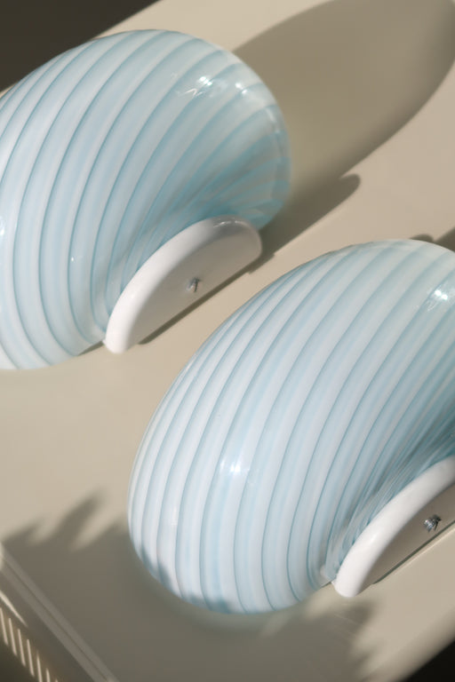 Smukke vintage Murano væglamper i fin blå nuance med swirl i glasset. Mundblæst i Italien, 1970erne, og formentligt aldrig brugt. Perfekt størrelse til din entré, i køkkenet, på badeværelset eller som læselampe i soveværelset. Super nemme at montere. Størrelse 22x15 cm. 