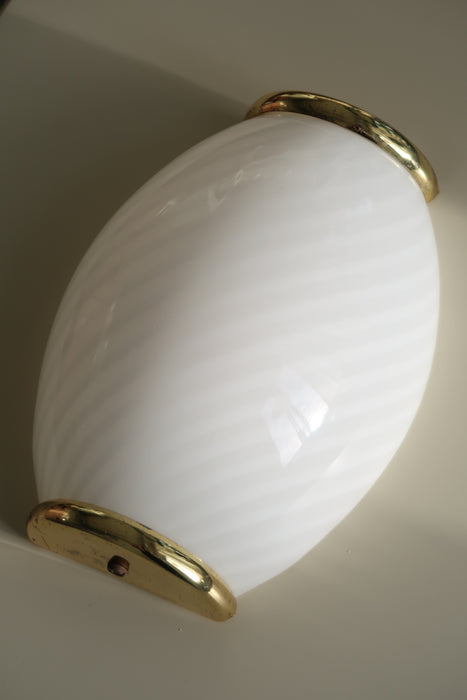 Smuk vintage Murano væglampe i opal hvid med swirl mønster i glasset. Mundblæst i Italien, 1970erne, og har messing beslag. Perfekt størrelse til din entré, i køkkenet, på badeværelset eller som læselampe i soveværelset. Meget lette at montere. Størrelse H:23 cm B:15 cm D:7 cm 