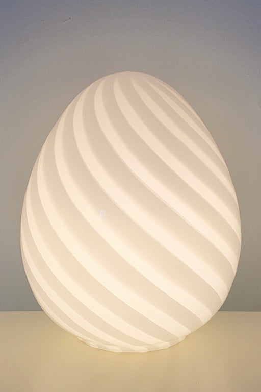Vintage Murano egg lampe i hvid glas med swirl. Mundblæst i en smuk oval form som et æg og er derfor kendt som ''egg lamp''. Helt fantastisk, skulpturel lampe. Håndlavet i Italien, 1960/70erne, og kommer med ny hvid ledning. ⁠H: 20 cm D: 16 cm