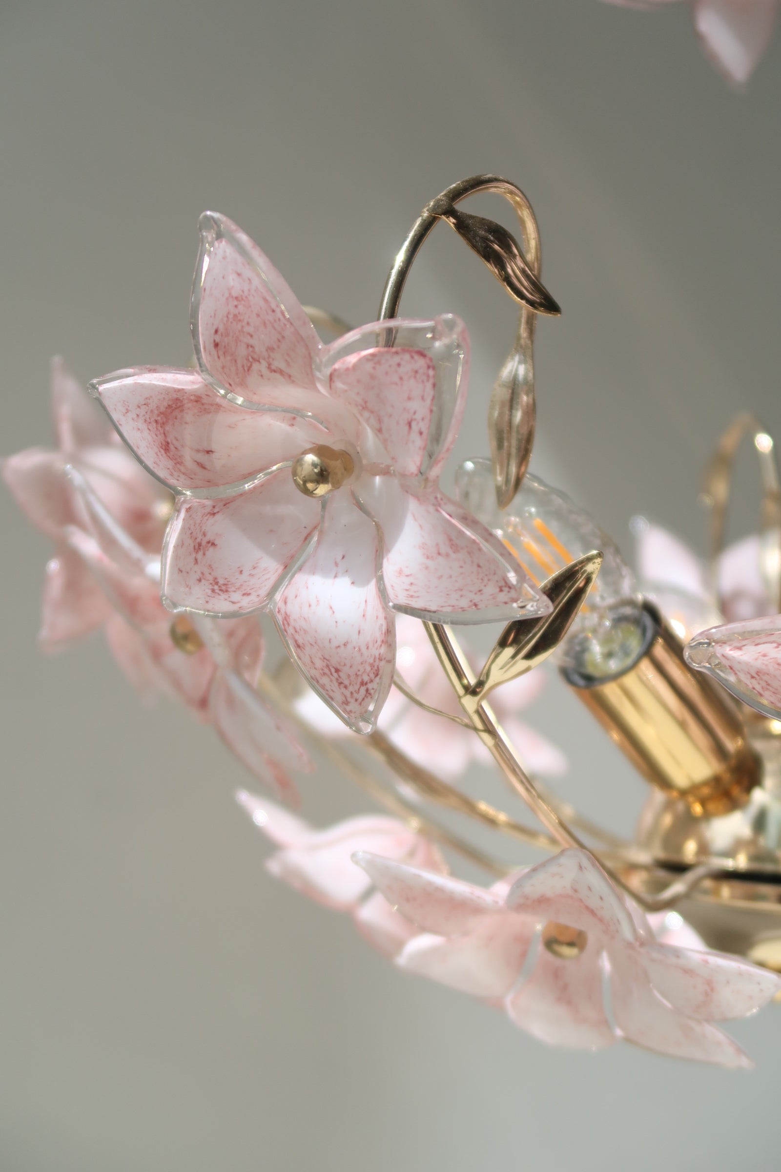 Smuk vintage Murano fiori lysekrone. Lampen består af 17 mundblæste lyserøde og hvide glasblomster sat på stel i patineret messing. Den har 3 (E14) fatningsholdere. Håndlavet i Italien, 60erne
