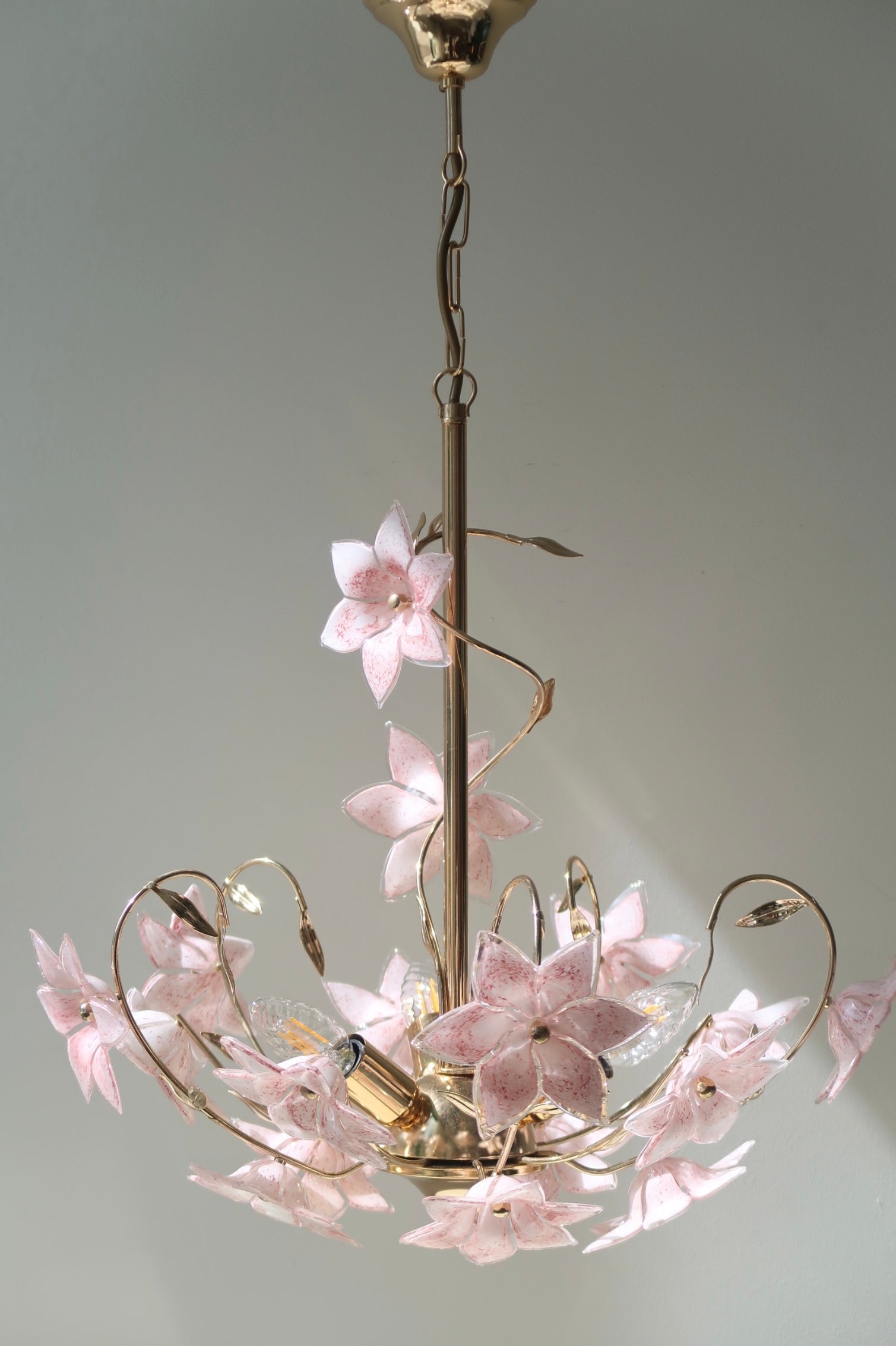 Smuk vintage Murano fiori lysekrone. Lampen består af 17 mundblæste lyserøde og hvide glasblomster sat på stel i patineret messing. Den har 3 (E14) fatningsholdere. Håndlavet i Italien, 60erne