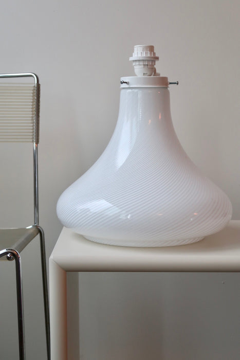 Vintage stor Murano lampefod i hvid glas med hvid swirl. Mundblæst i organisk form og har dobbelt fatning - dvs. den lyser både i glasbunden og i toppen. Lampen afgiver et meget hyggeligt lys og har en fantastisk swirl. Håndlavet i Italien, 1970erne. H:38 cm D:36 